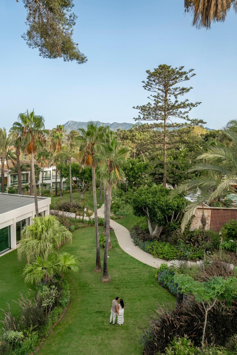 Couple in a garden of palm trees with hills in the distance